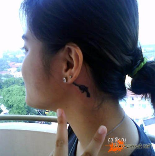 татуировка револьвер за ухом у девушки