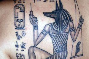 египетская татуировка на спине Анубис с весами и иероглифы